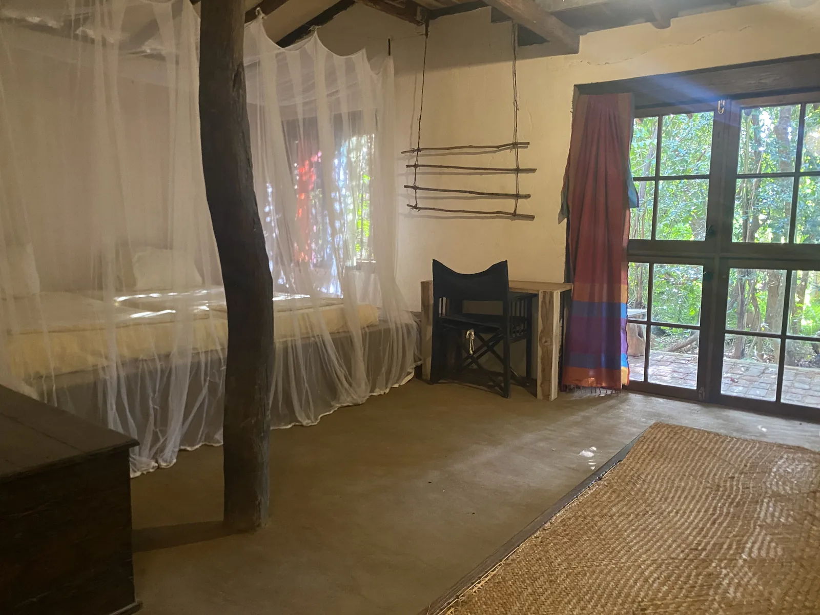 The bedroom looking out to the forest through tall doors